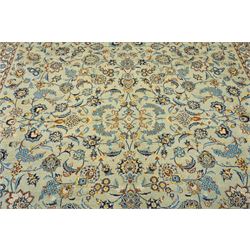 Central Persian Kashan hand-knotted carpet, pale blue field decorated with an all-over scrolling floral vine design incorporating stylized palmettes, rosettes and foliate sprays enclosed by a conforming floral vine border between multiple guard stripes, with cotton fringe ends 