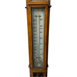 J Hicks - Hatton Garden London, - late 19th century carved oak cased Fitzroy barometer in a richly carved case with a carved crested pediment and square cistern cover, inverted opaline register reflecting FitzRoy's predictions and a scale from 27 to 31 inches of barometric pressure, with a thick bore cistern tube and adjustable rack and pinion twin vernier, fitted with a glazed snail bulb mercury thermometer recording the air temperature in both Fahrenheit and Celsius. Mercury clean and present.
James Joseph Hicks was born in Ireland, however, early in his life he moved to London where he was apprenticed to the instrument maker Louis P Casella. In 1860 he went into business in his own right as a scientific instrument maker at 8 Hatton Gardens. In 1864 he was granted membership to the British Meteorological Society and exhibited instruments at the Royal Society Exhibitions between 1876 and 1913. Hicks was one of London's most prolific and eminent barometer makers. 