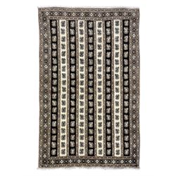Persian ivory ground rug, the field divided into stripes decorated with stylised flower heads, the border with repeating cross motifs within guard stripes 