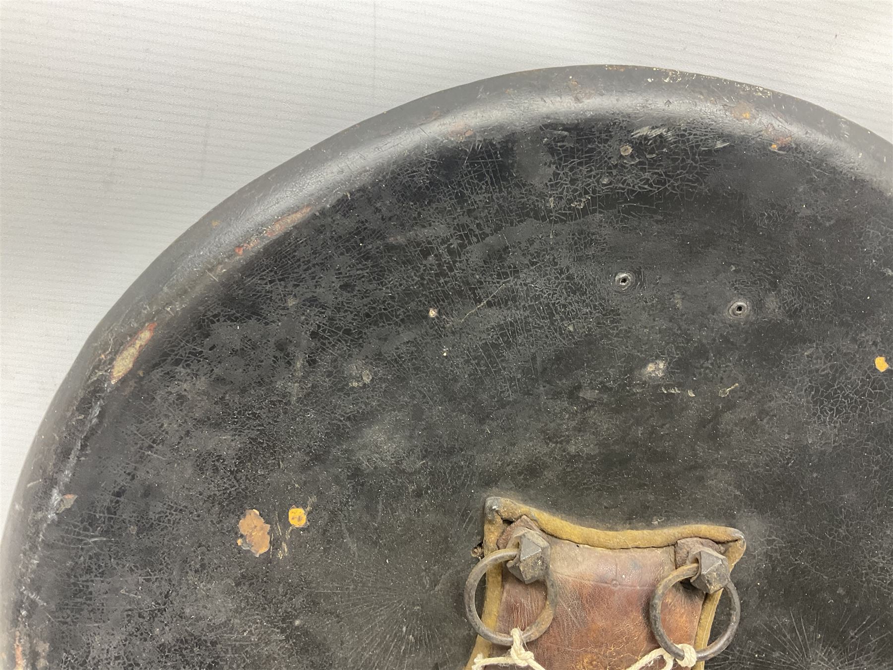 Indian black lacquered hide shield/dhal, of circular convex form with strongly outward-turned brim, fitted at its centre with four metal bosses, each of hemispherical form, with traces of silvered foliate decoration, the bosses corresponding on the inside with four iron rings for enarmes D49cm