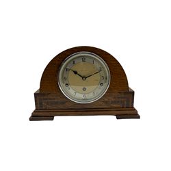 An English chiming mantle clock by Walker & Hall in an arched oak case with rosewood inlay, eight-day spring driven movement with a lever platform escapement, Westminster and Whittington chimes and chime/silent provision, dial with silver effect chapter ring, upright Arabic numerals and minute track, steel spade hands and concave glass within a chrome bezel.

