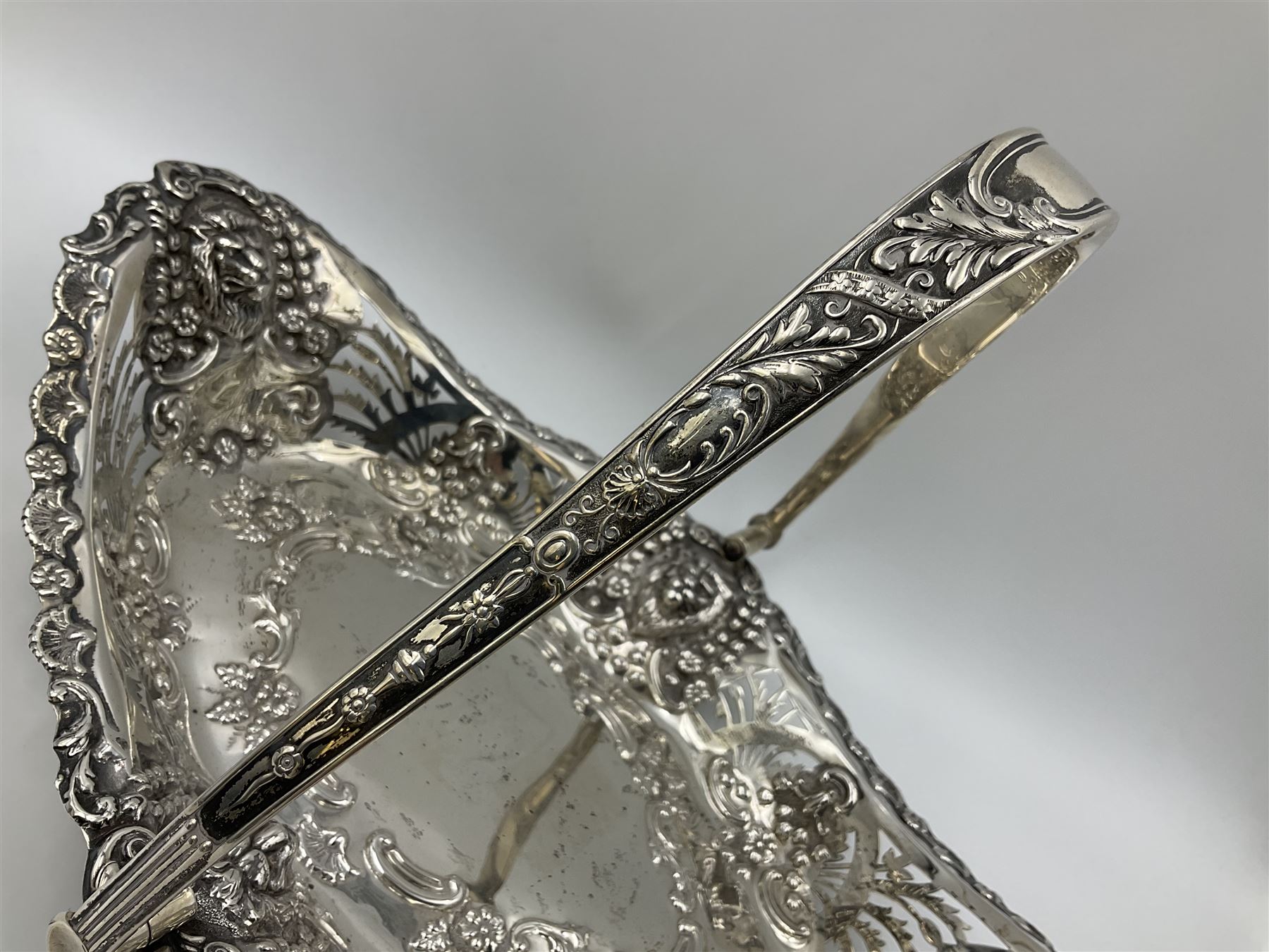 Edwardian silver swing handled basket, of navette form, with four repousse lion masks to each corner and with pierced and embossed floral, scroll and shell decoration to sides, base and handle, hallmarked Charles Horner, Birmingham 1906, height including handle H20cm
