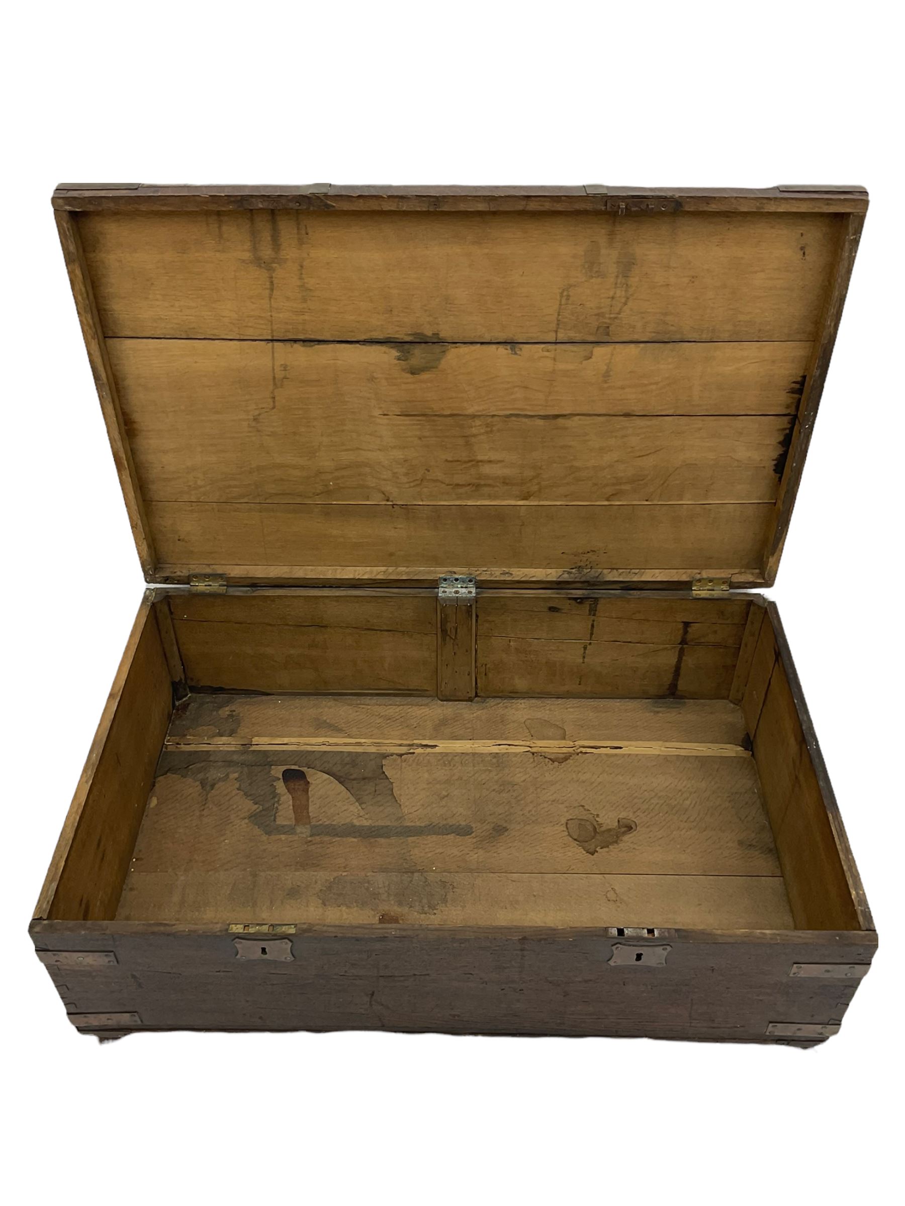 Early 19th century oak low blanket chest, metal strapped and bound, two carrying handles to either end, on castors