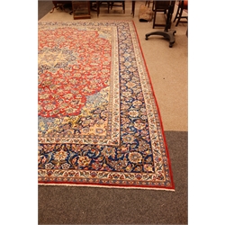  Meshed multicoloured carpet, red field with central floral medallion centre and spandrels with repeating palmette striped border, 437cm x 320cm  