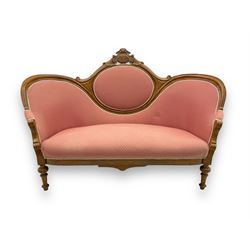 Late Victorian walnut framed double spoon back sofa, shaped crest rail with central carved medallion over curved back with pink upholstery, scrolling arms with additional carvings, on turned supports