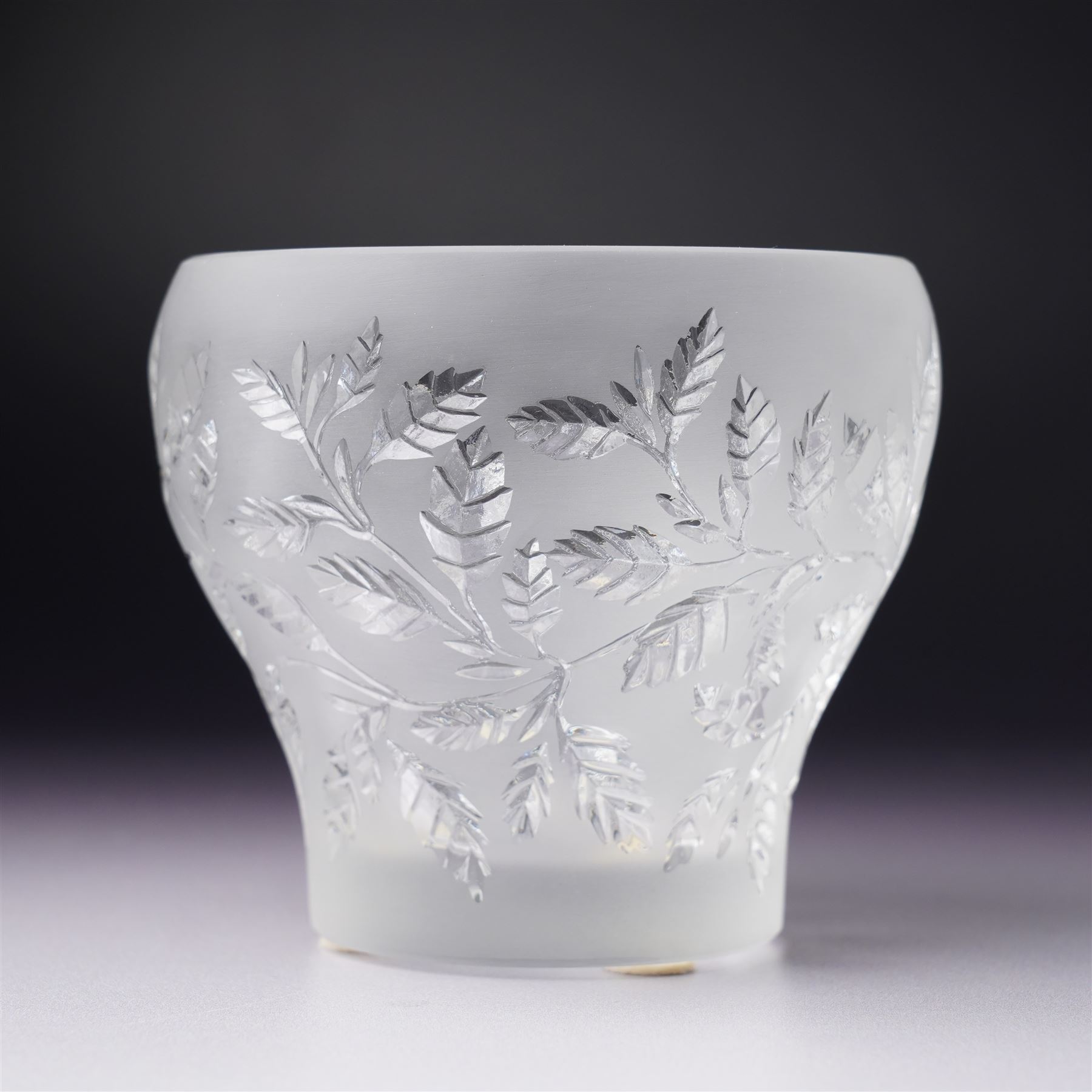 Three Lalique frosted glass tea light holders, decorated with the coriander and basil patterns, and another with trailing leaves, marked Lalique France to base, H7.5cm