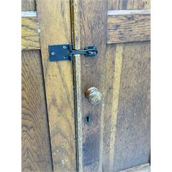 The North of England School Furnishing Company Limited Darlington - early 20th century oak school cupboard, projecting moulded cornice over two panelled doors, fitted with shelves, on chamfered plinth base 