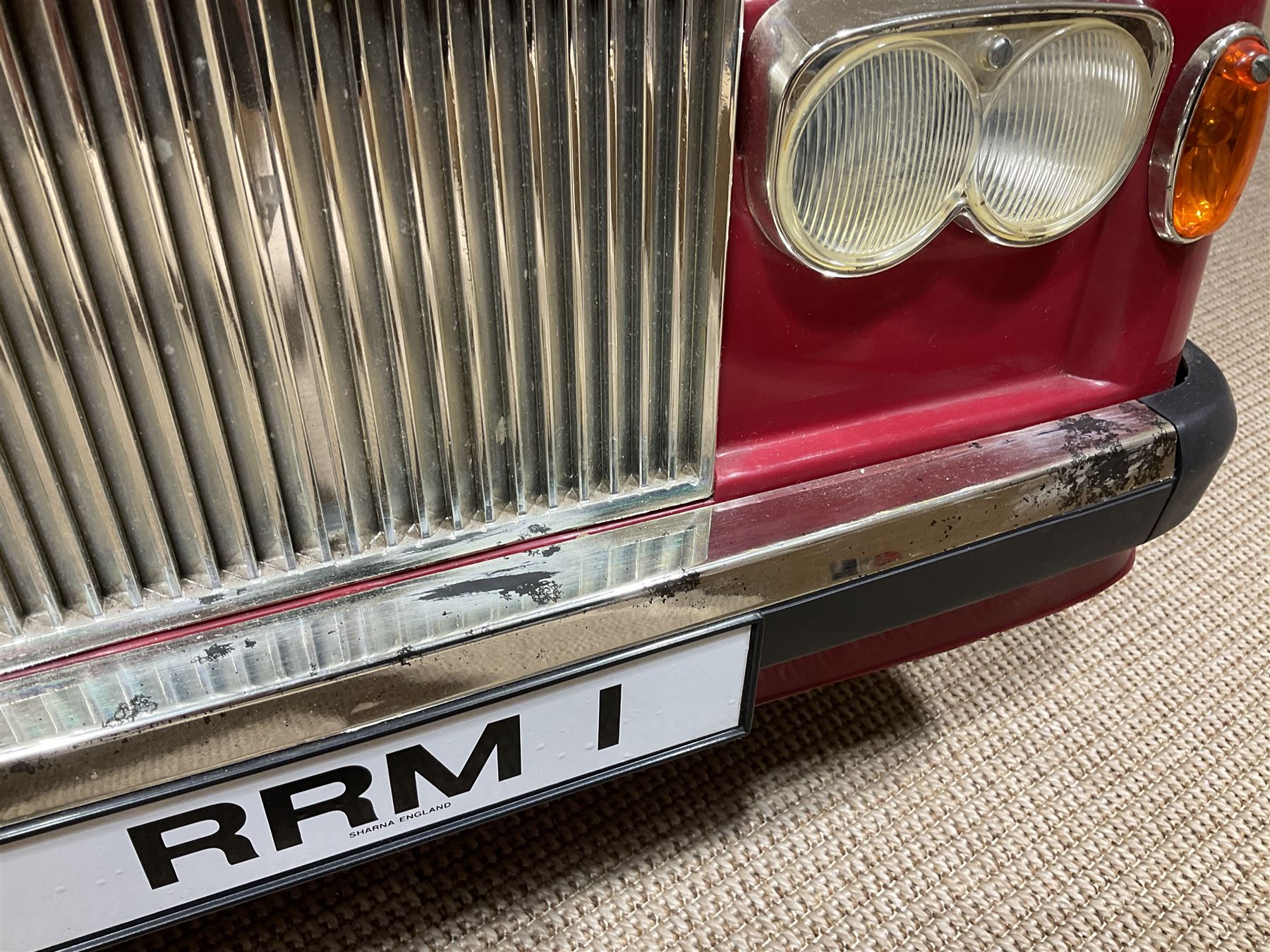 Early 1980s Rolls-Royce Corniche 'pedal' car by Sharna Tri-ang Limited, registration no.RRM1, steel chassis with treadle pedals, red moulded plastic body with flexible plastic 'Spirit of Ecstasy' car mascot on the radiator cap, opening boot lid, dashboard with decals of faux wood panelling and gauges, battery powered working electric lights, Sharna 235/70HR15 wheels with Rolls Royce hub caps, L123cm; together with two keys on RR fob, instructions manual in wallet, date stamped 17 November 1983, toy road tax disc dated 31.01.83/84 and original battery charger. 
Auctioneers Note: In 1983 Sharna Tri-ang Ltd., based at Lumb Mill in Droylsden, Manchester, took over from Tri-ang Toys at Merthyr Tydfil. They went on to launch a new range of toys based on children's TV programs, such as Knight Rider, Street Hawk, Roland Rat, The A-Team, The Get A-Long Gang and Postman Pat, as well as Rolls-Royce Corniche pedal cars, which were available in red, white or blue. 