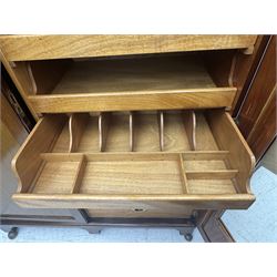Wylie & Lochhead, Glasgow - early 20th century mahogany and satinwood double wardrobe, projecting cornice over panelled doors, interior fitted with mirrored door, shelves, drawers, hooks and hanging rail, raised on bracket supports with ceramic castors