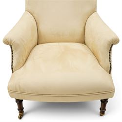 Sofas & Stuff - pair of ‘Thistle’ armchairs upholstered in neutral fabric, each with gently sloping back, padded scroll arms with close-set stud detailing, loose seat cushions, raised on turned wooden legs with brass castors