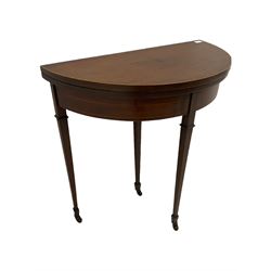 Edwardian inlaid mahogany demi-lune card table, fold over top revealing baize lined playing surface, raised on square tapered supports with peg feet and castors W76cm
