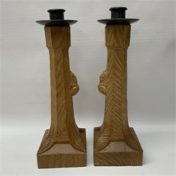 Mouseman - pair of tooled oak candlesticks, wrought iron sconce with drip tray over tapered octagonal column carved with mouse signature, terminating to stylised leaf carved square base, by the workshop of Robert Thompson, Kilburn
