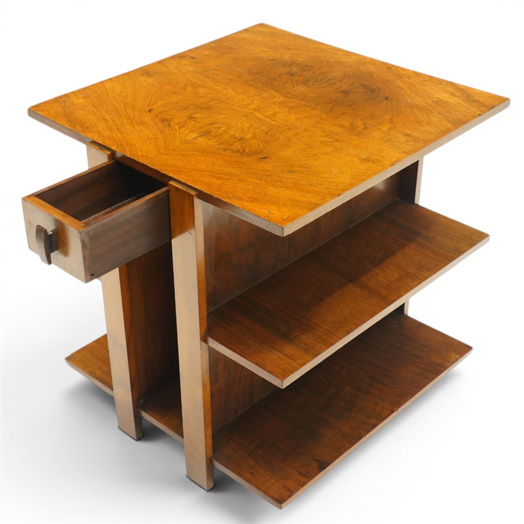 Art Deco walnut coffee table, square book-matched veneered top over single frieze drawer with brass handle, flanked by open side shelves, raised on rectangular end supports