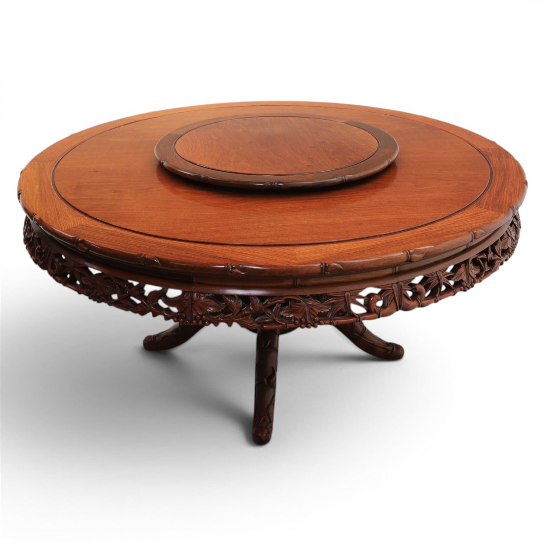 20th century Chinese ornately hardwood dining table and chairs, circular table with 'Lazy Susan' top with pierced carved frieze, raised on a quadriform base with carved foliate detail, the chairs en suite with carved pierced detailing  