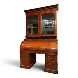Victorian mahogany cylinder roll-top bookcase-secretaire, projecting cornice over twin glazed doors enclosing two shelves, the cylinder roll-top enclosing fitted interior with sliding drawer, hinged compartments, correspondence drawers and pigeon-holes, the twin pedestals fitted with three graduating drawers to each side, on plinth bases with castors