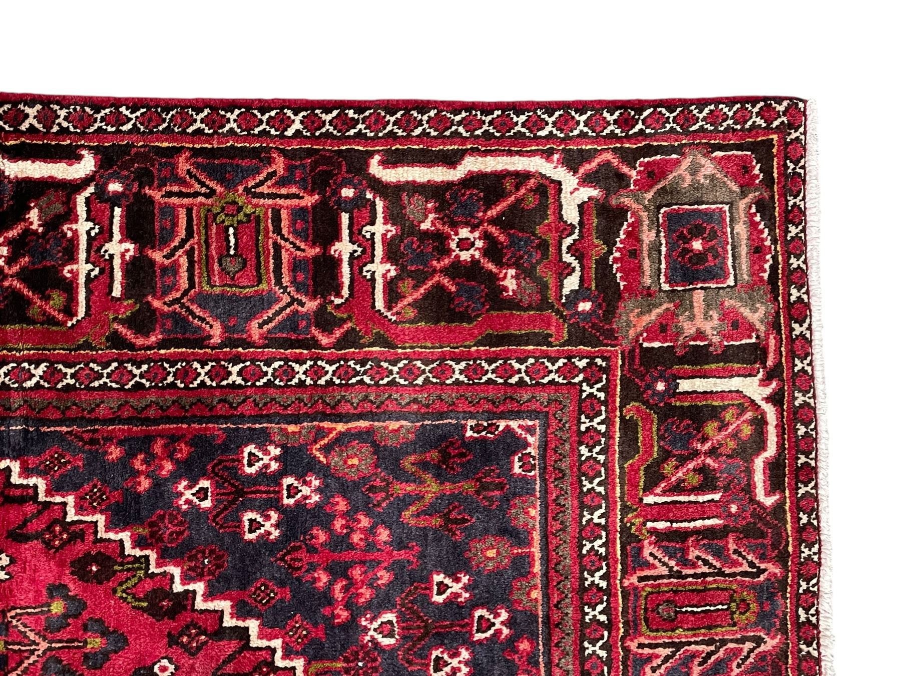 Persian Joshaghan crimson ground rug, stepped lozenge medallion surrounded by repeating foliate lozenge motifs, the border decorated with stylised plant motifs, within geometric guard stripes 