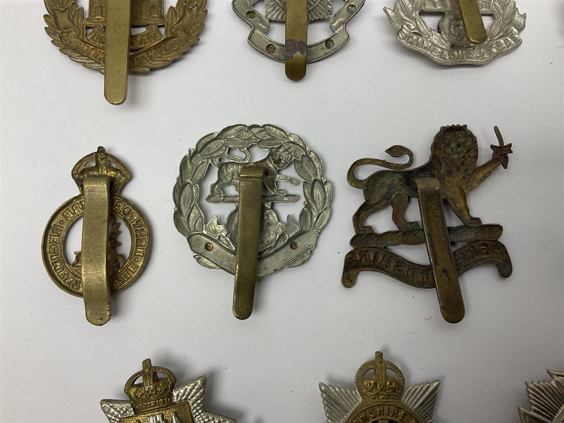 Twenty cap badges including Hertfordshire, Royal Sussex, Cambridgeshire, Hampshire, Notts and Derby, East Surrey, Herefordshire, South Lancashire, Devonshire, Bedfordshire, Durham Light Infantry etc (20)