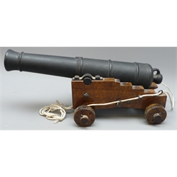  Small black painted cast iron model of a Canon, 36cm barrel on oak carriage, L41cm  