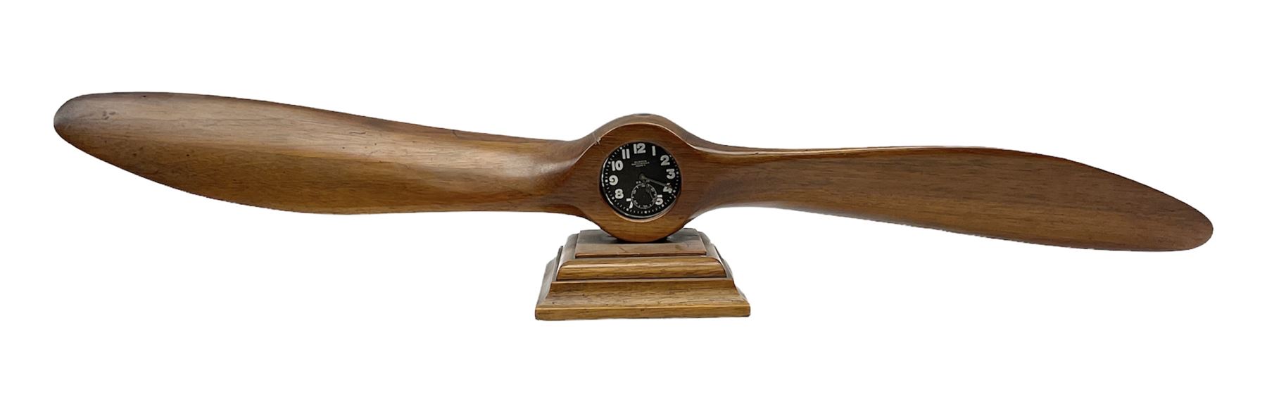 Early 20th century novelty small propeller mantle clock reputedly made by an apprentice at Blackburn Aircraft Works, Beverley & Hull in 1914, the mahogany case loosely inset with a WW1 DOXA Royal Flying Corps pocket watch, the black dial inscribed ' 30-Hour Non-Luminous Mark V.' number BE11653 with subsidiary seconds dial, the back marked with a capital 'A' above a broad arrow, mounted on a stepped square base L67cm