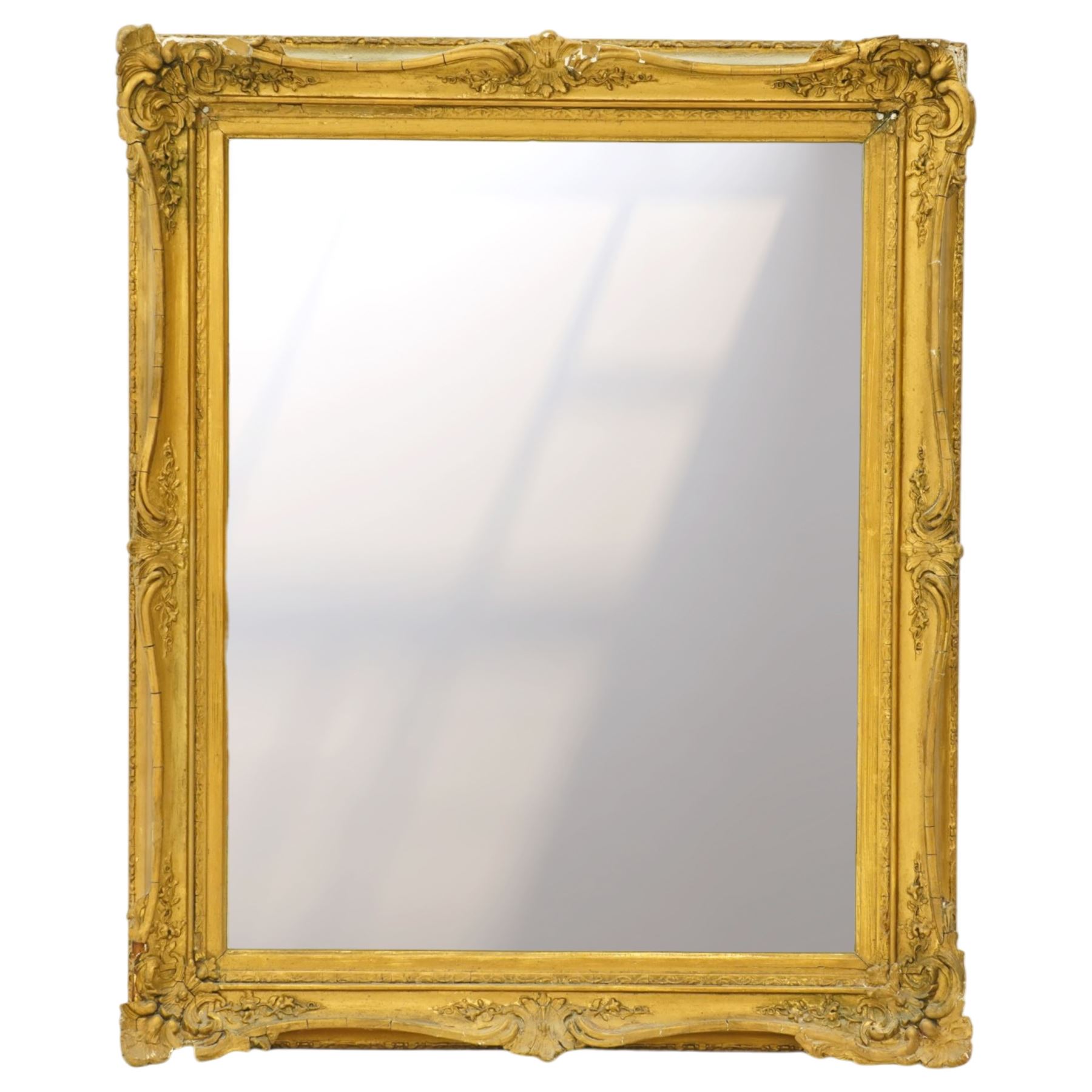 French style gilt composition wall mirror, the rectangular plate within a swept frame moulded with scrolling foliage and shell motifs