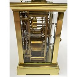 Early 20th century brass and bevelled glass repeater carriage clock with alarm, the angular and cylindrical ribbed handle and repeater button over stepped cavetto cornice, white enamel Roman dial with Arabic subsidiary alarm set dial, twin train eight day movement striking the hours and half on coil, separate alarm mechanism train, stepped moulded and plain faced base, with leather travelling case