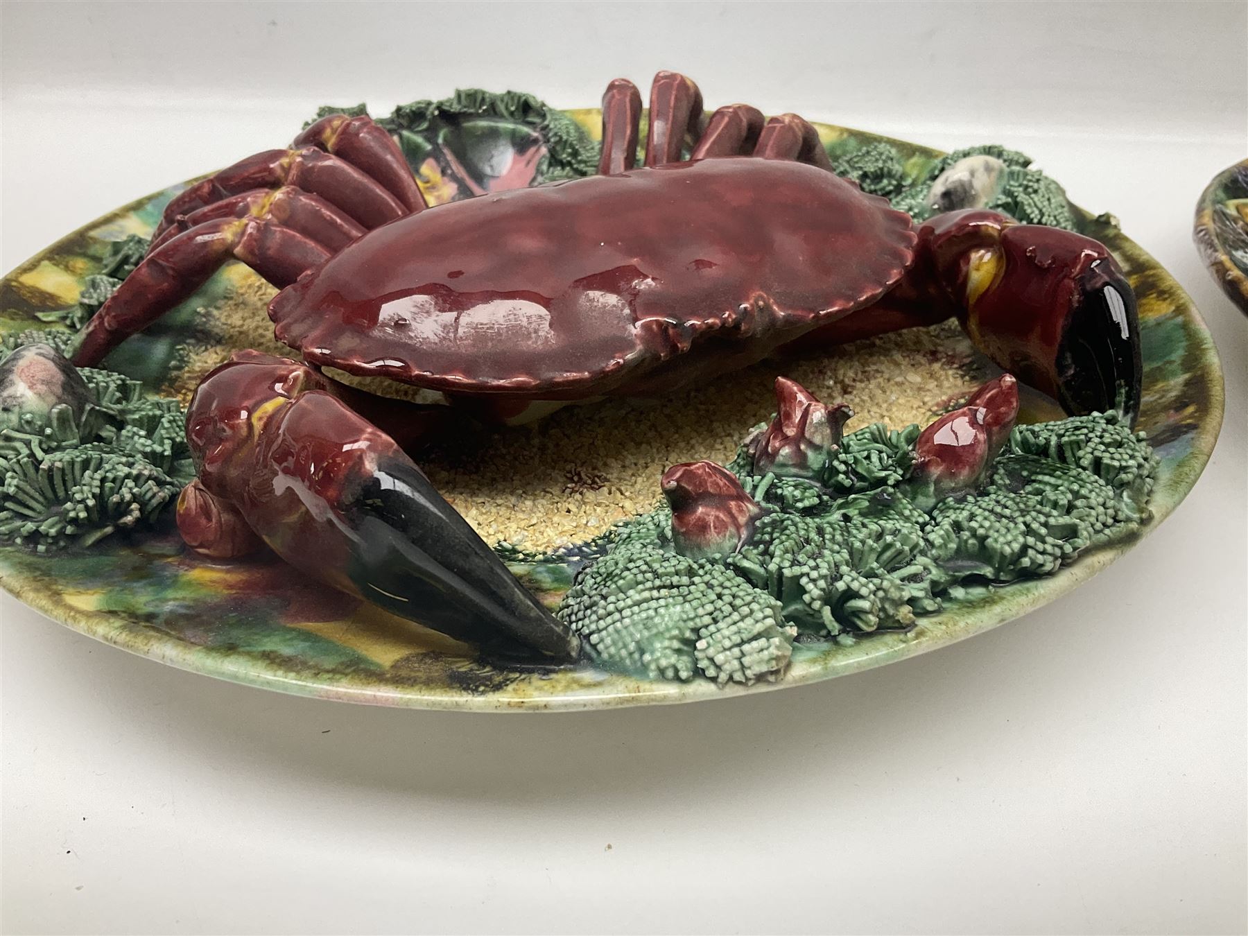 Two 20th Century Portuguese Palissy style Majolica wall plates, one depicting a crab, the other a lobster each to the centre modelled in relief surrounded by encrustations and shells, both with impress marks beneath, D34cm