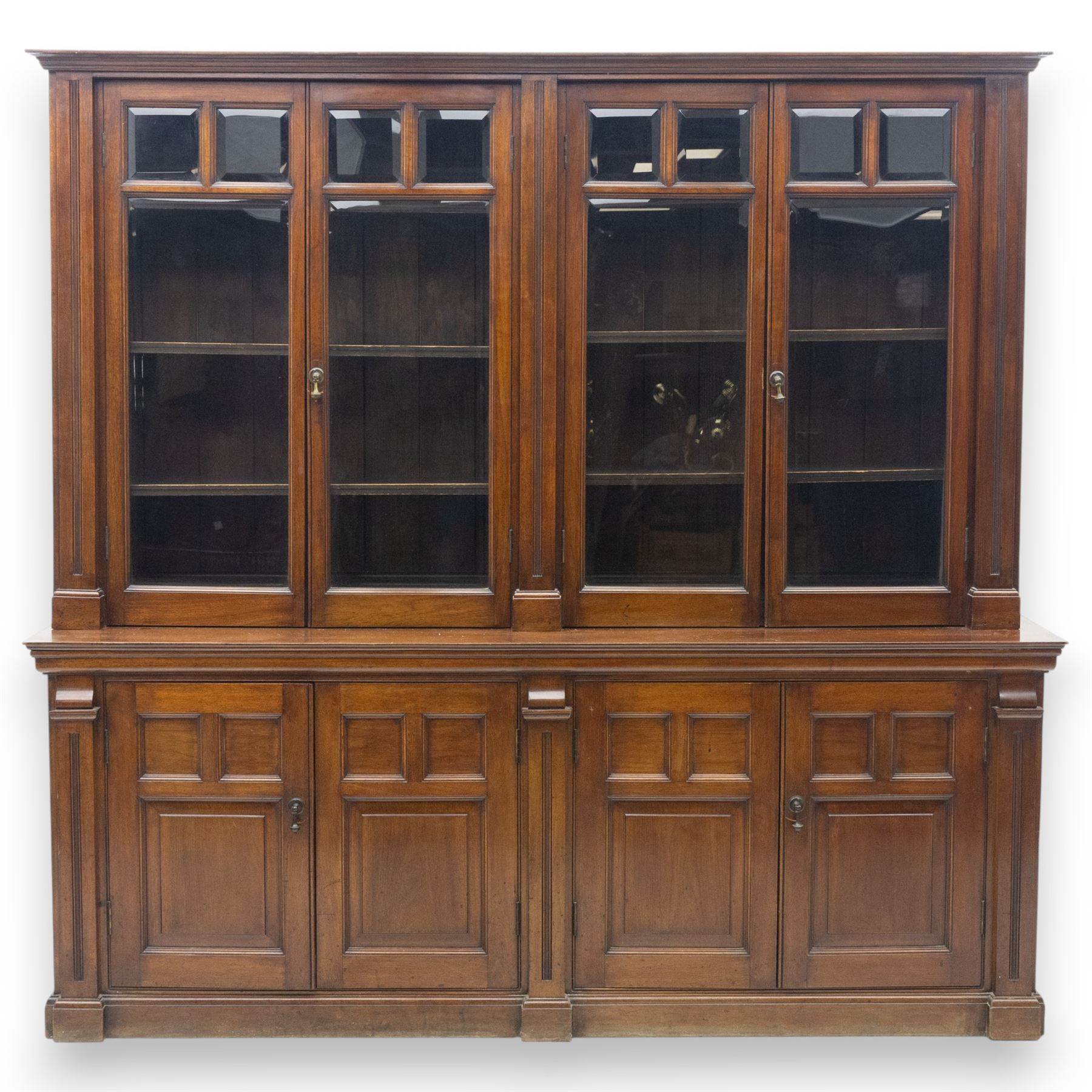 Late 19th century walnut library bookcase, fitted with four display doors with astragal bevelled panes, raised upon a four cupboard base with fielded panel doors