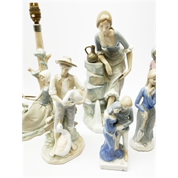 A group of figurines, to include a large Nao example, H32.5cm, and a Lladro table lamp, (a/f). 