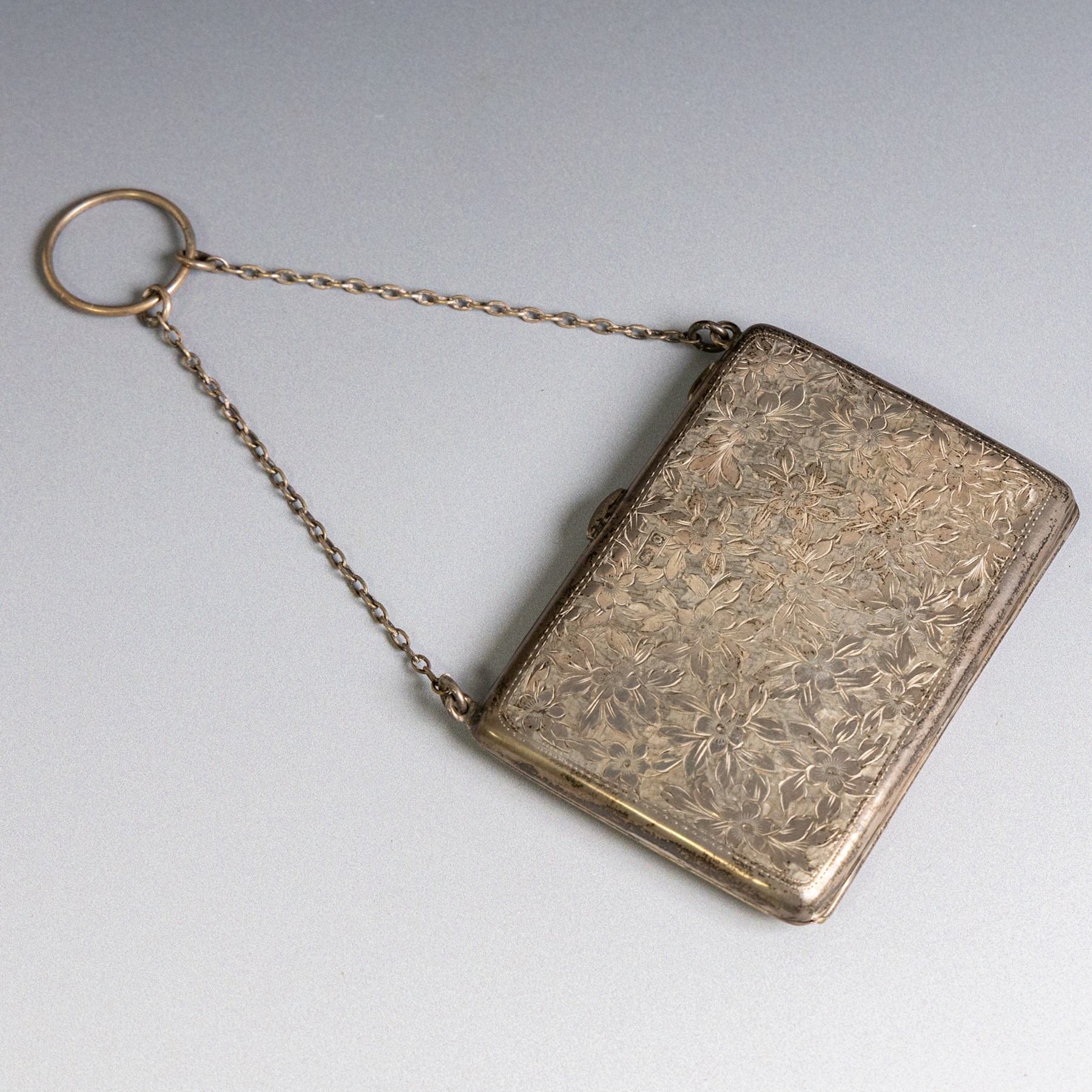 Early 20th century silver coin purse, with floral decoration and finger chain, hallmarked together with an early 20th century cigarette case,  with engraved initials, hallmarked and a silver filigree cigarette case