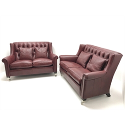 Pair Duresta two seat high back sofas upholstered in deep buttoned maroon leather, ebonised supports on chrome castors, W150cm