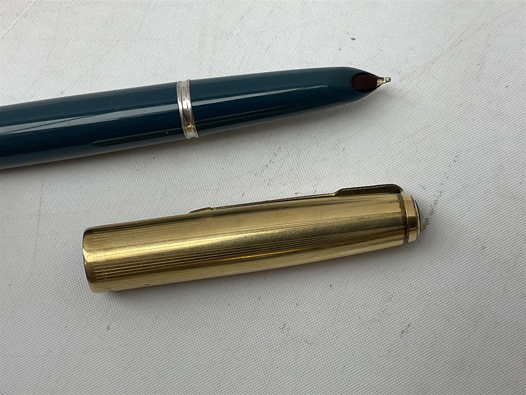 Five Parker fountain pens with gold caps, to include 65 Consort Insignia with rolled cross hatch gold cap, two Parker 51 fountain pens in burgundy with 12ct rolled gold caps, together with two further 51 examples in blue and black, all with stamped lids
