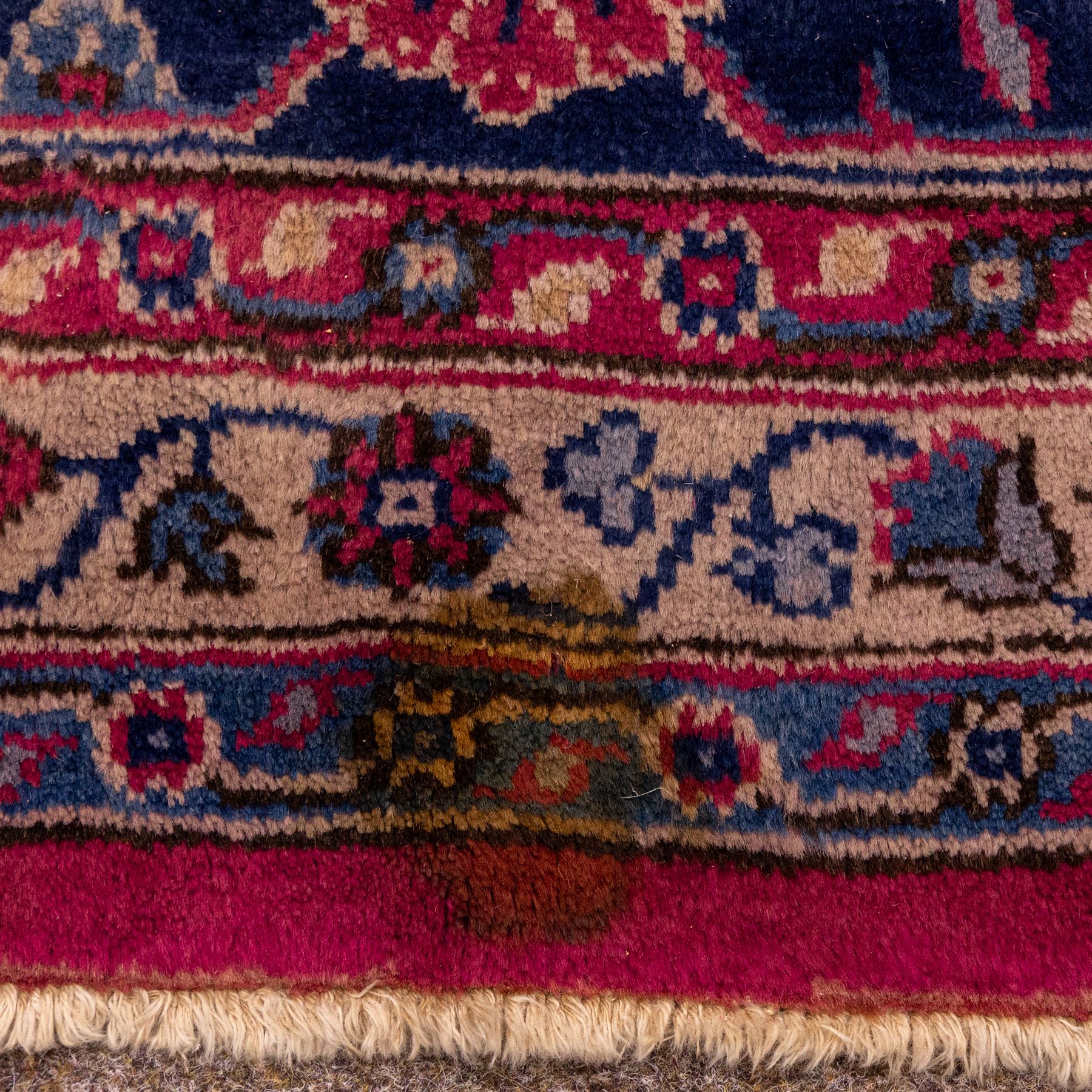 Large Persian-style mahal-type hand-knotted carpet, of rectangular form with a deep crimson field decorated with an all-over arrangement of stylized floral sprays and palmettes, with a central subtle medallion composition enclosed by a dark navy main border of scrolling floral motifs between narrow guard stripes with fringe ends 
