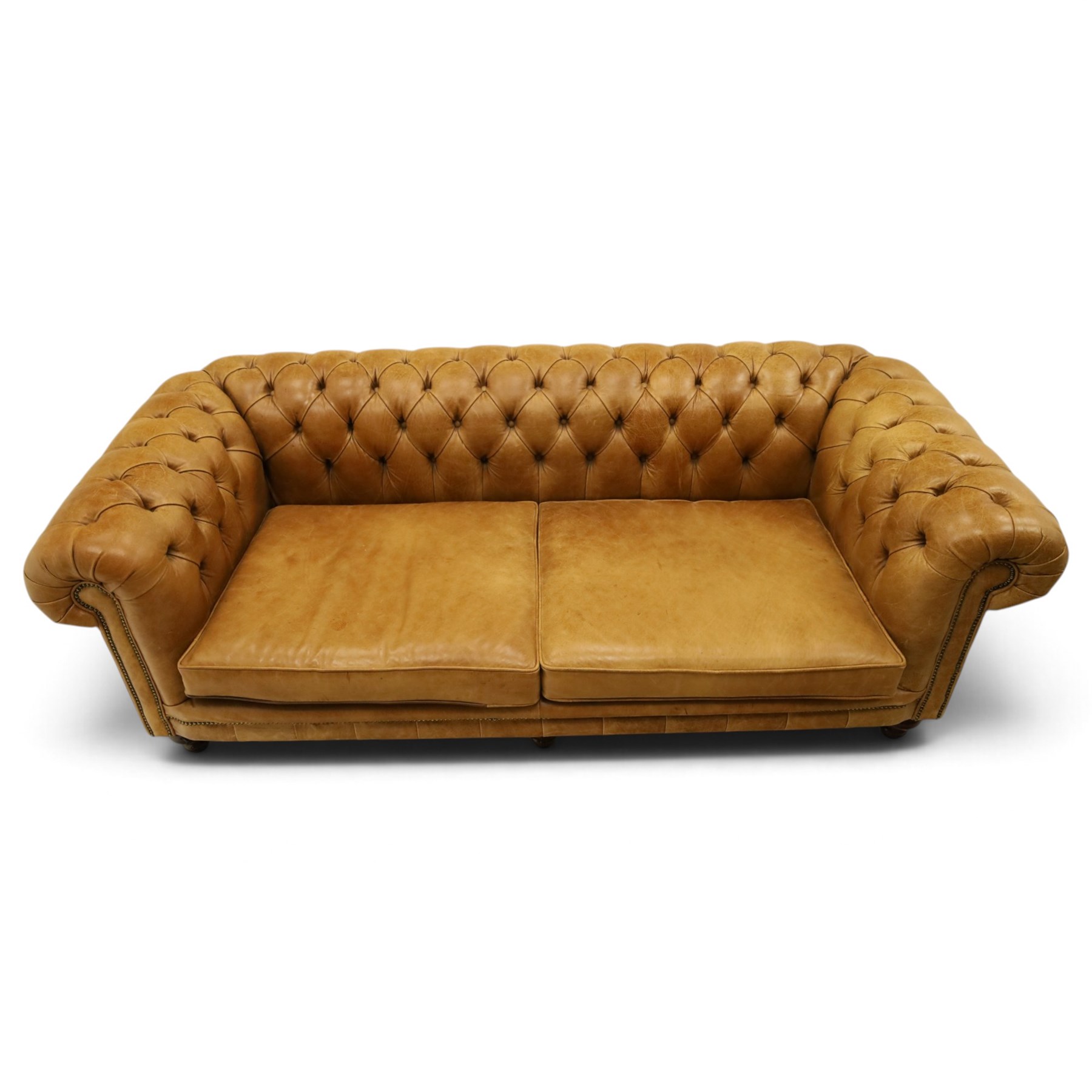 Distinctive Chesterfields - traditional shape four seater Chesterfield sofa, the rolled back and arms upholstered in deep-buttoned tan leather with matching loose seat cushions, raised on six turned supprorts