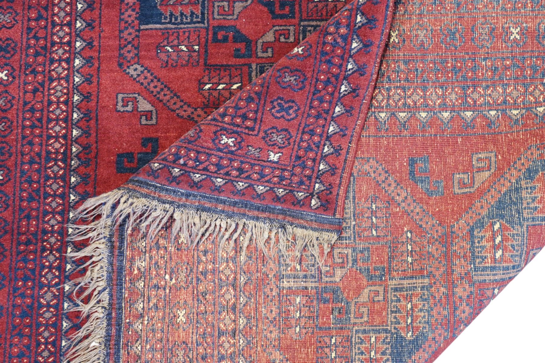 Afghan red ground Bokhara rug, the field decorated with two rows of large Gul motifs, within geometric pattern borders 