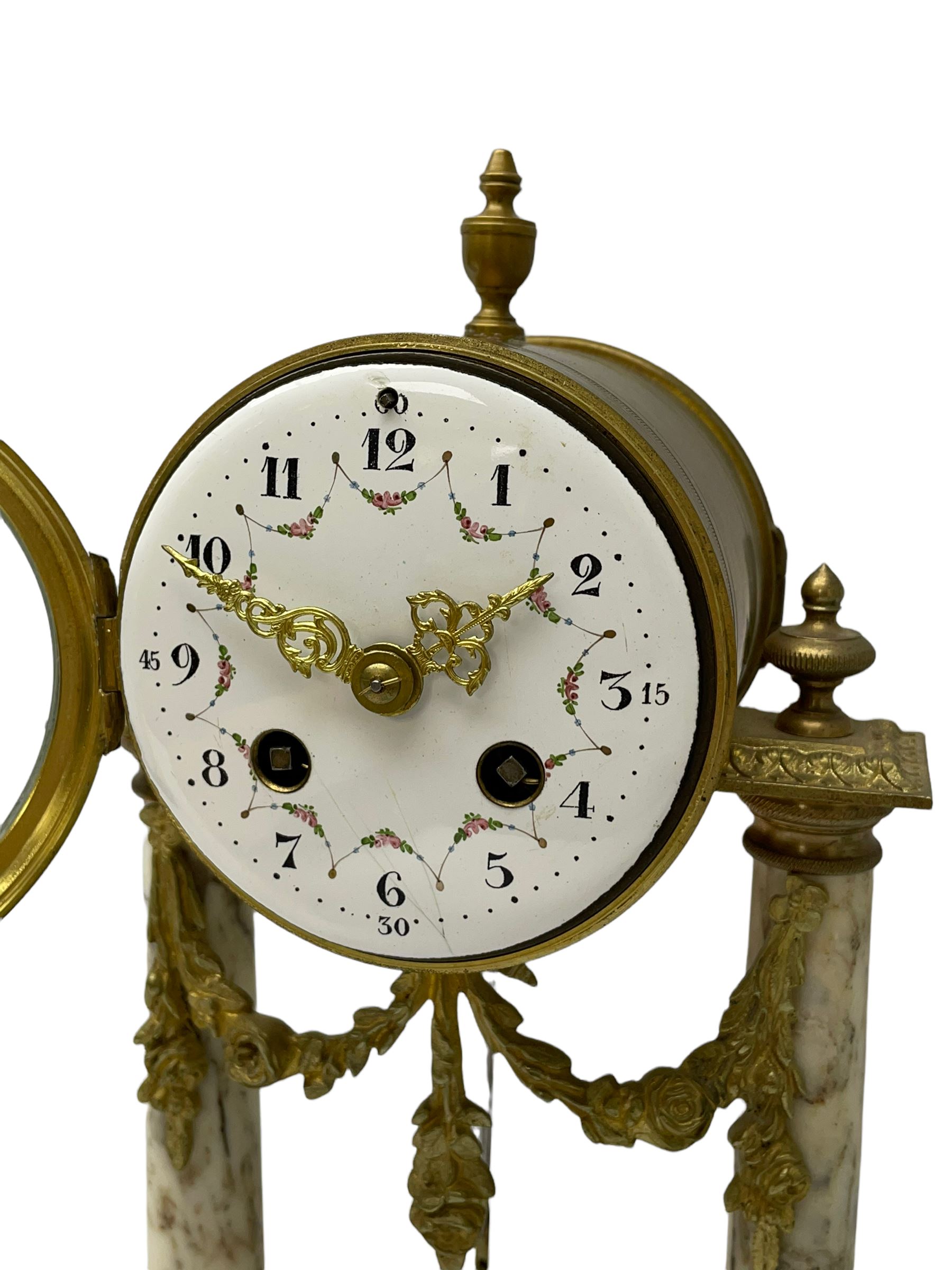 20th century French portico clock c1910 on a white veined marble base, gilt drum movement case supported between two marble columns with brass capitals and a suspended garland swag with a starburst pendulum beneath, enamel dial with Arabic numerals, floral decoration and Louis XV pierced gilt hands, convex glass and brass bezel, 8-day countwheel striking movement striking the hours and half hours on a bell. 




