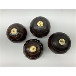 Four early 20th century lawn bowl balls, to include a pair with inset initialled ivory roundels, and mother of pearl roundels, and another pair of inset faux ivorine roundels. 