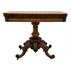 Victorian figured rosewood card table, fold-over swivel top with circular baize lining, moulded frieze with stylised flower head carving to corners, turned column with egg and dart decoration, on quadruple splayed c-scroll carved supports, with brass castors