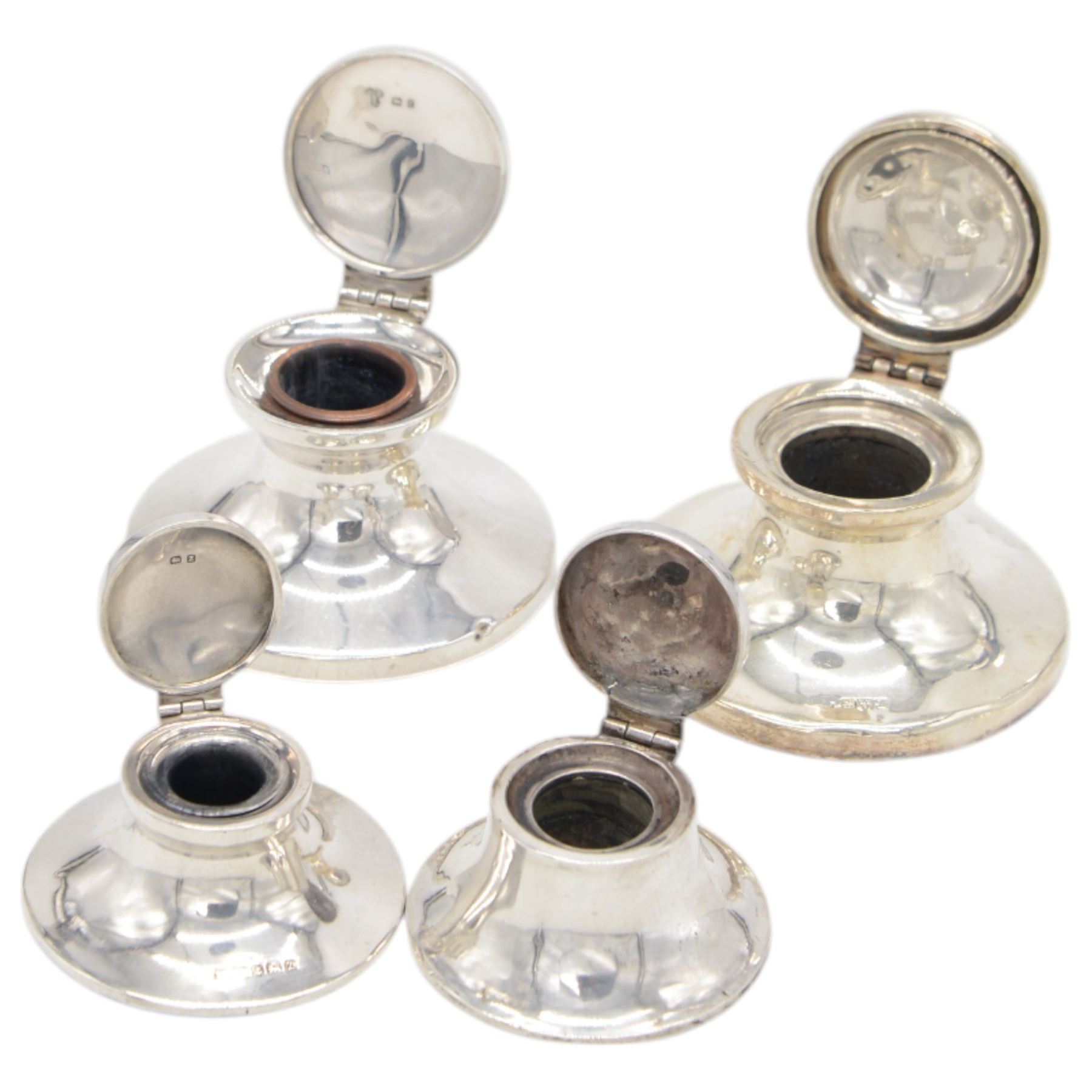 Four early 20th century silver mounted capstan inkwells, all of typical circular form with hinged covers, all hallmarked 