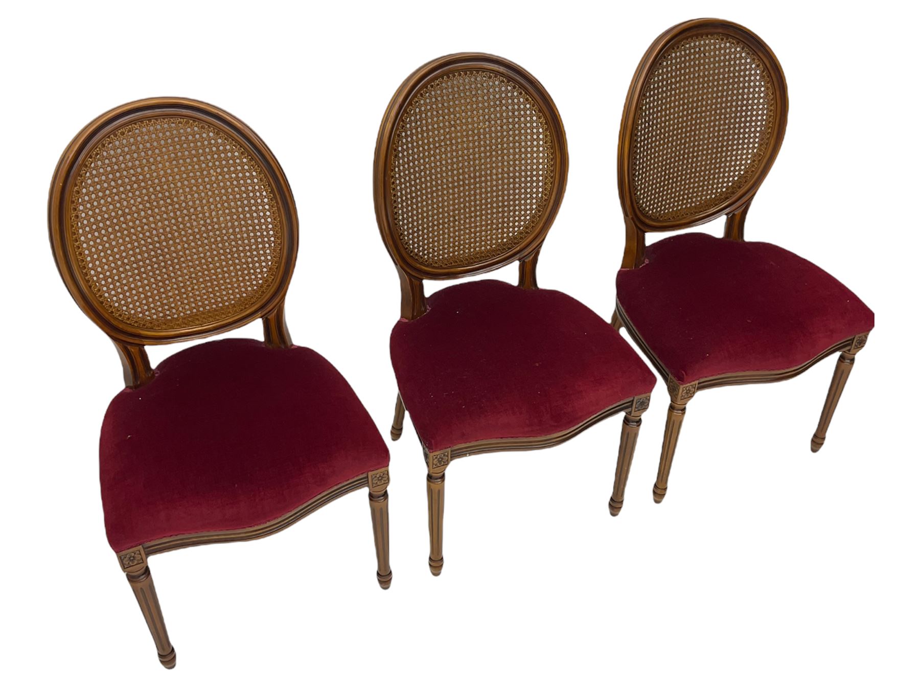 Set six French style walnut finish dining chairs, oval cane bergere backs over serpentine seats upholstered in red, flower head carved fluted supports
