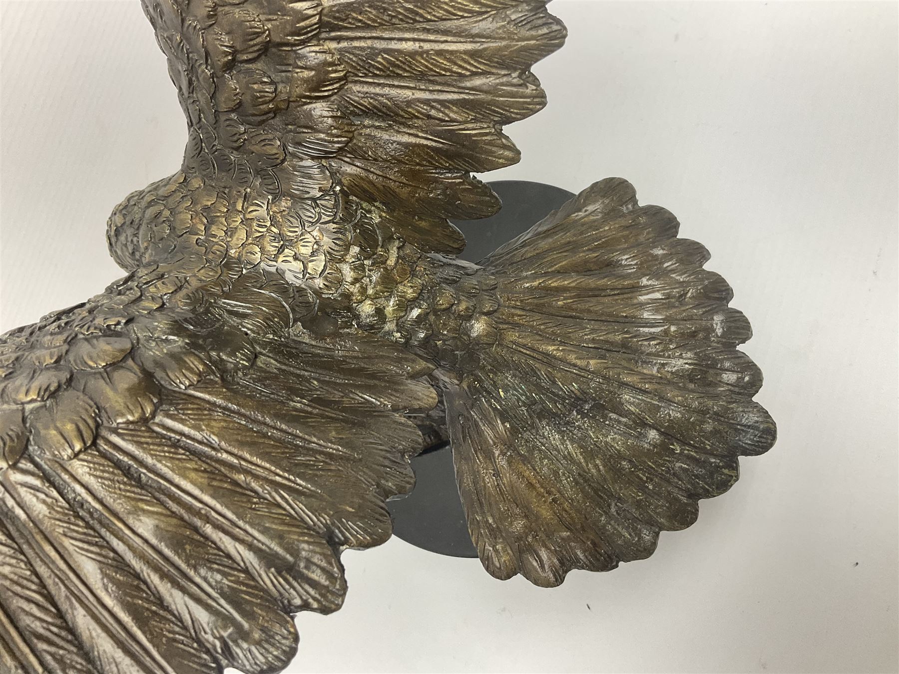 Bronze eagle, modelled in a standing position with wings spread, raised on a black veined marble circular plinth base, H29cm