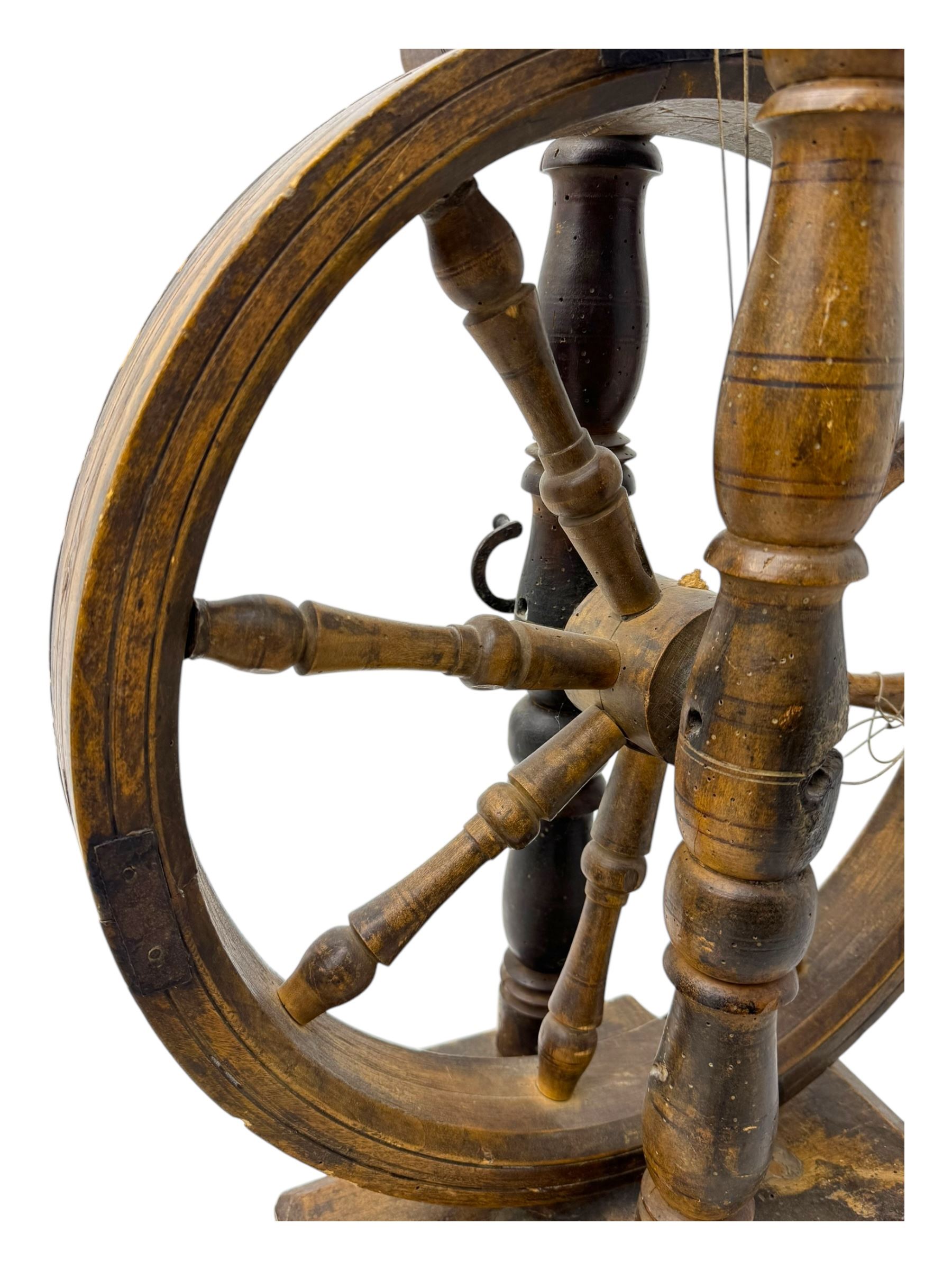 Late 19th century turned beech spinning wheel, upright form with single treadle, triangular base, and a flyer and bobbin assembly surmounted by a turned finial.
