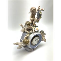 A Lladro mantel clock modelled as a globe with inset clock, surmounted by four putti and floral garlands, with blue printed mark and impressed 5973 beneath, H29cm.