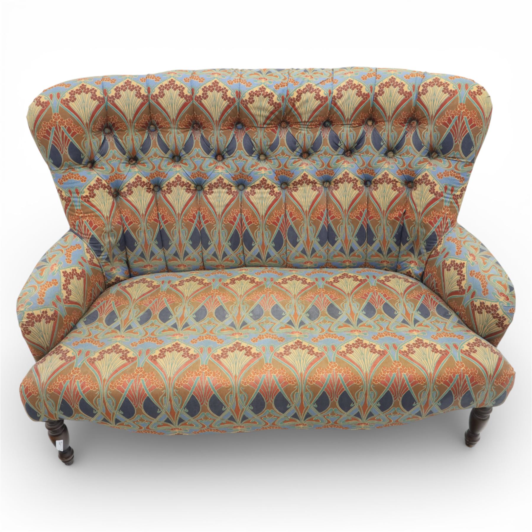 Late 20th century Liberty upholstered two seater sofa, the shaped back and arms with deep buttoned upholstery, covered in Art Nouveau fabric with stylised floral and foliate motifs, loose scatter cushions en suite, raised upon turned tapering front supports and swept rear legs