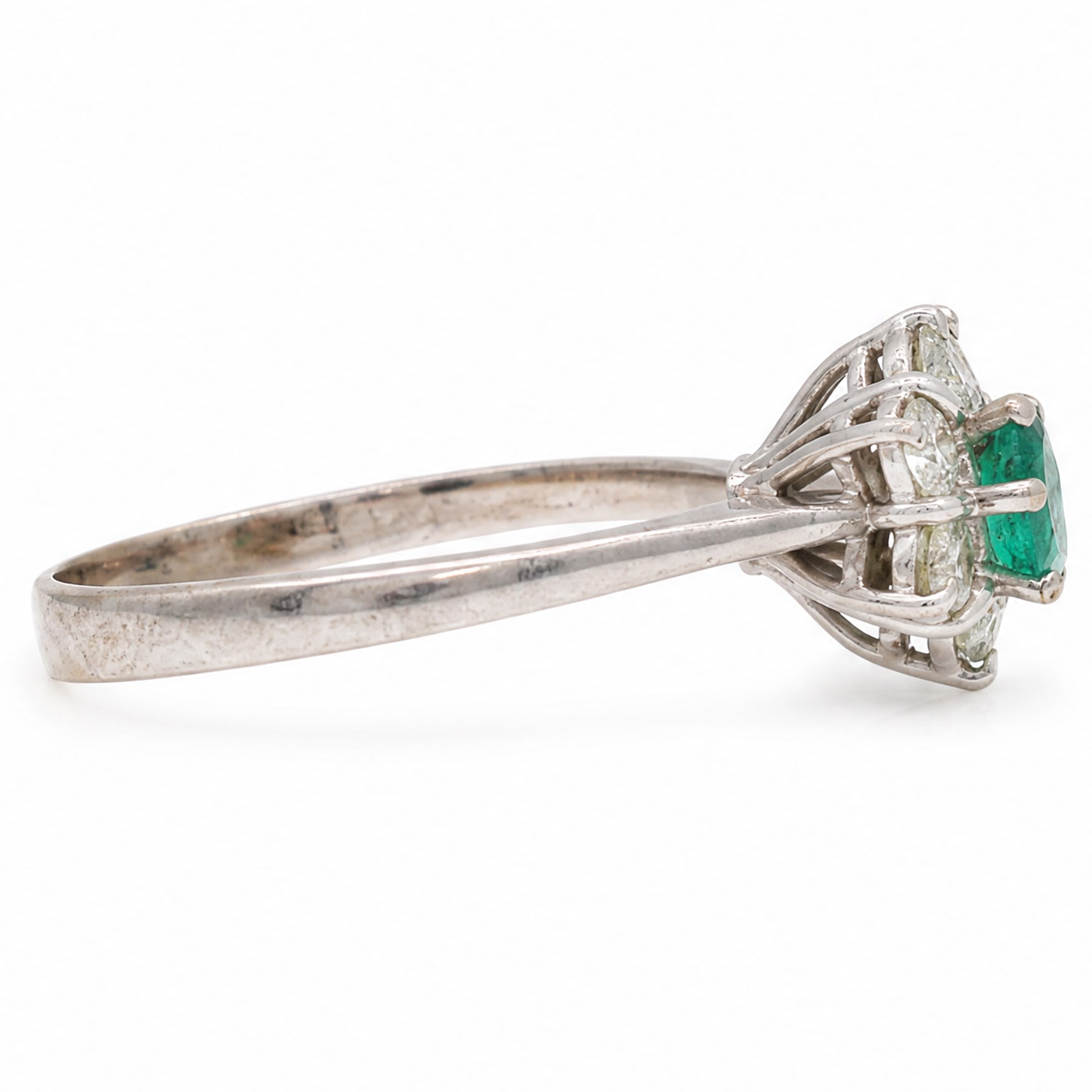 White gold emerald and diamond cluster ring, single oval cut emerald of approx 0.25 carat, surrounded by six round brilliant cut diamonds, stamped, total diamond weight approx 0.30 carat