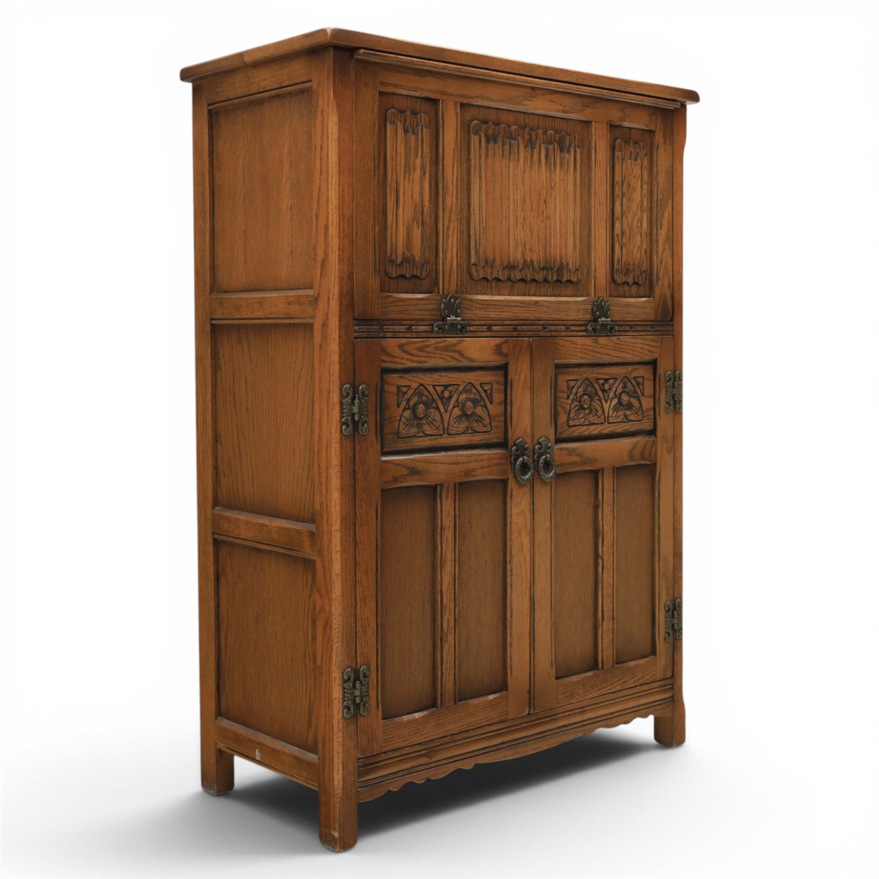 Old Charm - carved oak bar with three bar stools and associated Old Charm drinks cabinet, carved top with channels for glassware beneath, bar surface above glazed panels, shelves for glassware to the back, associated Old Charm drinks cabinet with fall front linenfold carving, above twin doors with shelved interior