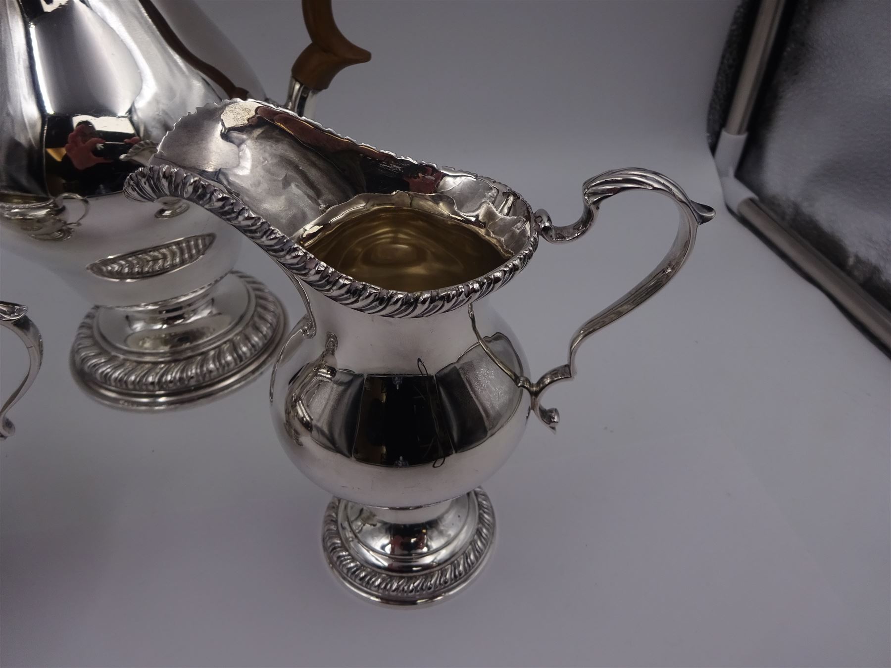 Mid 20th century three piece silver coffee service, comprising coffee pot, milk jug and twin handled open sucrier, of waisted form upon circular domed foot,  with oblique gadrooned rim, the milk jug and sucrier with acanthus capped handles, the coffee pot with wooden handle and finial, hallmarked William Comyns & Sons Ltd , London 1961, coffee pot H27.5cm