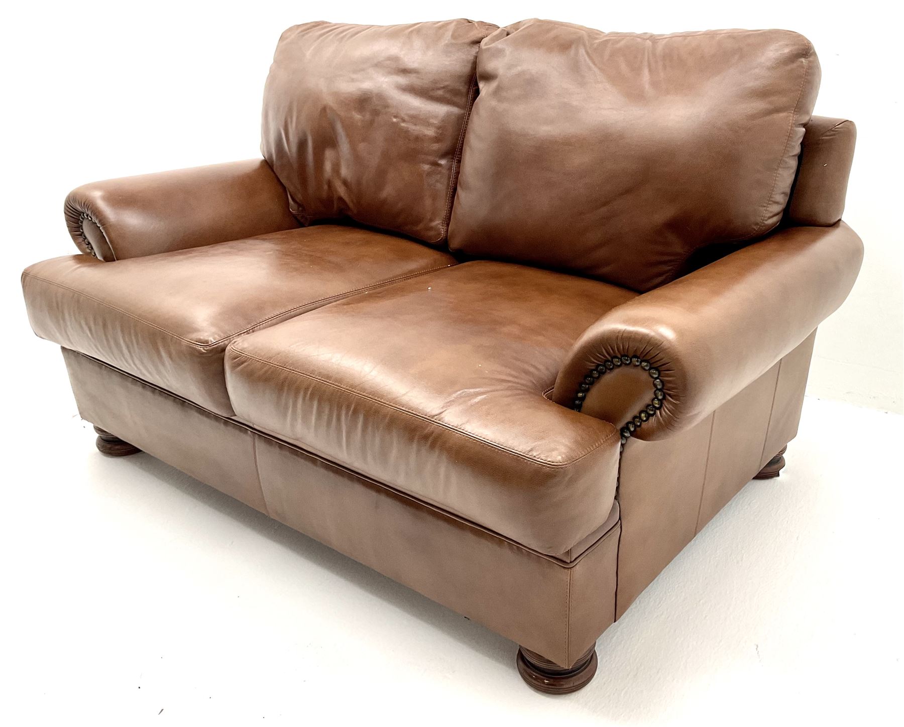 Three seat studded tan leather sofa, scrolling arms, turned supports (W190cm) with matching two seat (W155cm) armchair (W100cm) and footstool 