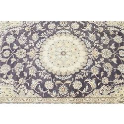 Central Persian Nain hand-knotted carpet, indigo field with central cusped medallion of radiating palmette form, enclosed with an elongated cartouche issuing network of scrolling vine work, arabesques and flowering sprays, surrounding ivory field of conforming design filled with foliate motifs and palmettes, spandrels of complimentary design with angular reserves, within principal border of ivory ground with scrolling vinery rosettes and arabesques, flanked by narrow guard stripes, with cotton fringe ends 