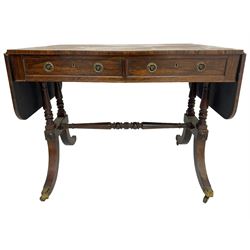 Regency rosewood sofa table, drop leaf rectangular top with rounded corners, fitted with two drawers and two opposing false drawers, raised on dual turned columns terminating in splayed feet united by turned stretcher, on brass cups and castors