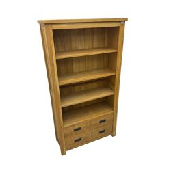 'Galloway' oak open wide bookcase, fitted with three adjustable shelves over four drawers, retailed by Alexander Ellis of Beverley